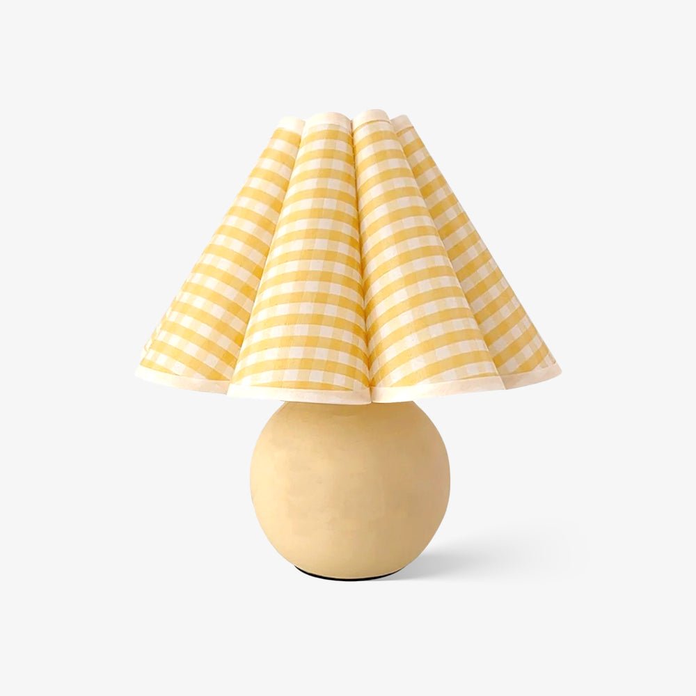 Shown here, a Clérachic table lamp with a yellow plaid pleated shade and a pale ceramic ball base, on a plain white backdrop.
