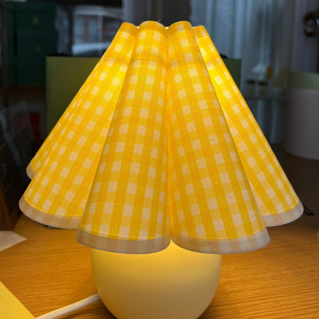 Close view of the glowing yellow plaid pleated shade on this Clérachic table lamp, lit from within.