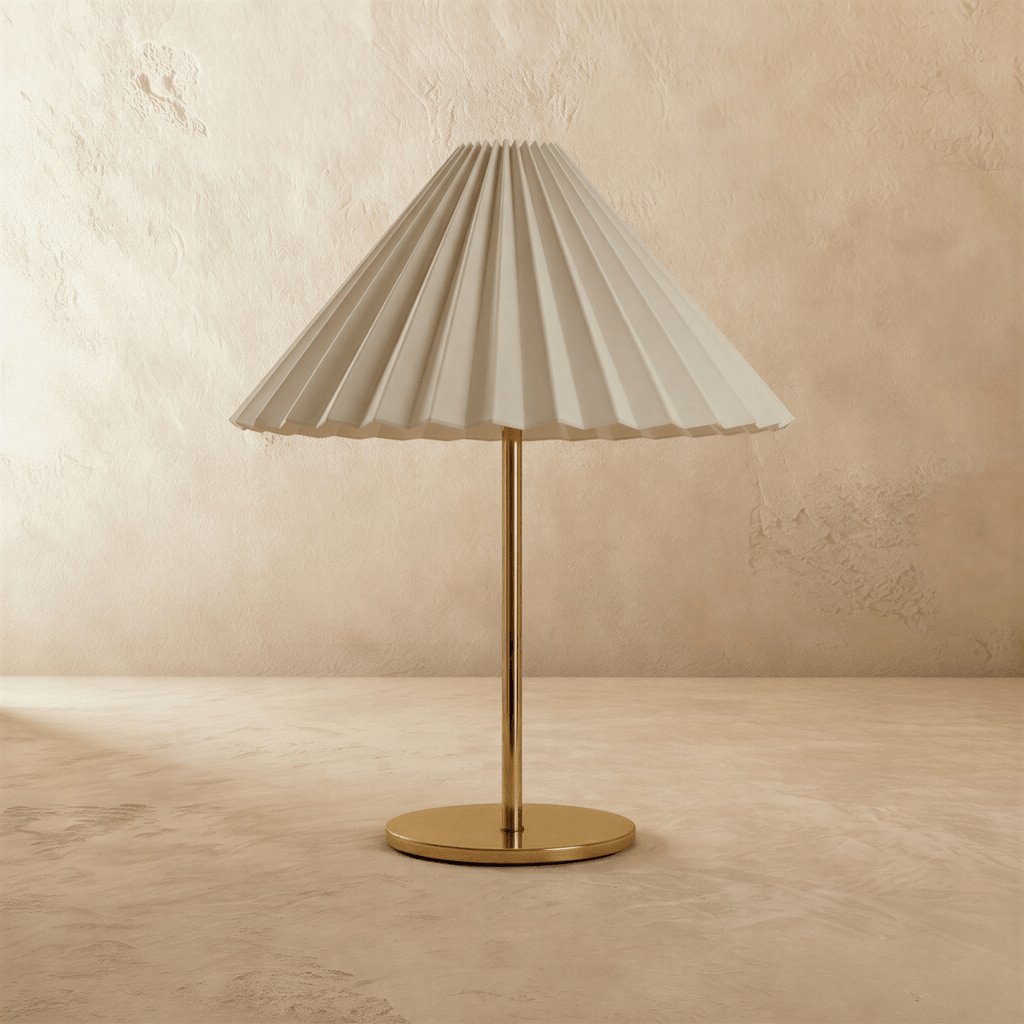 Clérachic table lamp with a pale grey-white pleated conical shade on a slim brass stem and flat round brass base, unlit, on limewash.