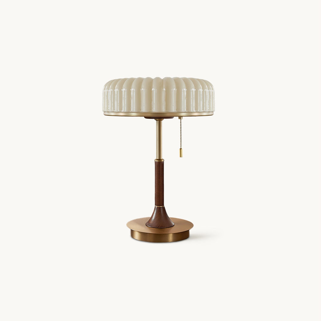 A Clérachic table lamp on a plain white backdrop, with a pleated beige shade, a walnut-wood stem and a round gold metal base.