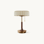 A Clérachic table lamp on a plain white backdrop, with a pleated beige shade, a walnut-wood stem and a round gold metal base.