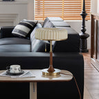 Shown here, a Clérachic table lamp on a small side table next to a black leather sofa, with a cup and saucer resting on a magazine.