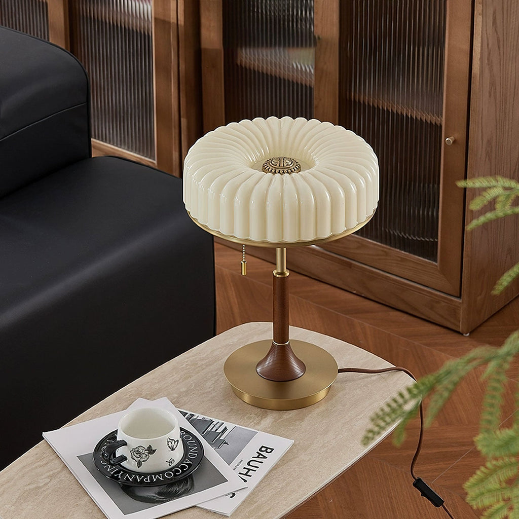 Seen from above, the pleated shade of this Clérachic table lamp shows its round brass-coloured centre, on a travertine side table.