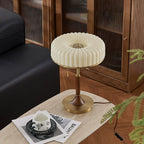 Seen from above, the pleated shade of this Clérachic table lamp shows its round brass-coloured centre, on a travertine side table.