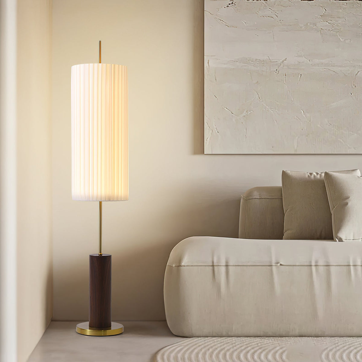 This Clérachic floor lamp with a walnut-colour base stands by a low cream sofa, with a plaster-textured artwork on the wall.