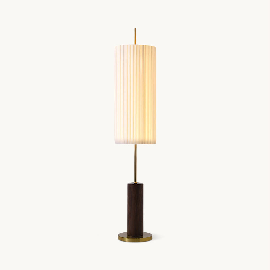 This Clérachic floor lamp on white, its softly lit pleated shade over a brass rod and a walnut-colour base with a brass foot.