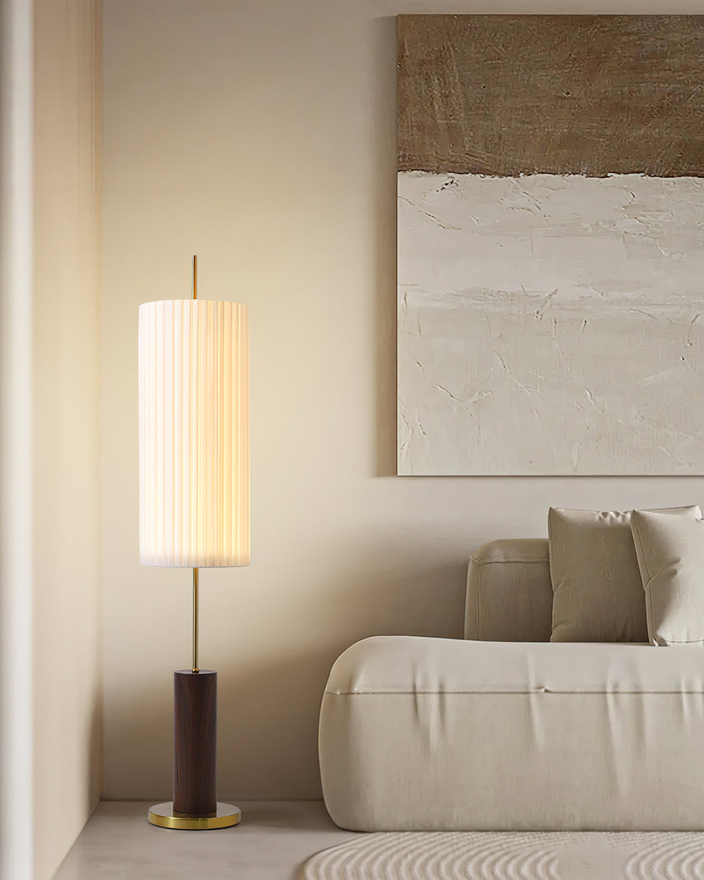 A Clérachic floor lamp with a walnut-colour base stands in a cream living room beside a sofa, under a textured abstract painting.