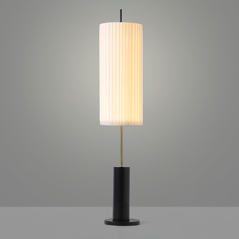 This Clérachic floor lamp with a black base against a mid-grey studio backdrop, its pleated shade lit from within.