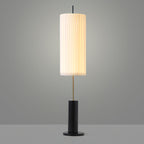 This Clérachic floor lamp with a black base against a mid-grey studio backdrop, its pleated shade lit from within.