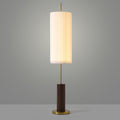 Walnut-colour base and brass foot of this Clérachic floor lamp, with the lit pleated shade on a slim rod against grey.