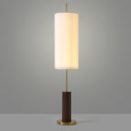 Walnut-colour base and brass foot of this Clérachic floor lamp, with the lit pleated shade on a slim rod against grey.
