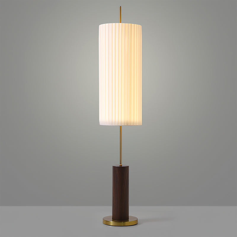 Walnut-colour base and brass foot of this Clérachic floor lamp, with the lit pleated shade on a slim rod against grey.