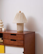 The Clérachic linen lamp, unlit, on a walnut sideboard, with a cream vase and a small bobbled candle beside it.