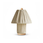 A sand-coloured version of this Clérachic pleated lamp, with a wooden finial and foot, on a white backdrop.