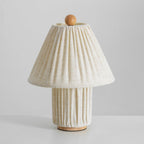 Unlit Clérachic linen lamp with a pleated shade, a matching base and a wooden ball finial, on a pale grey surface.