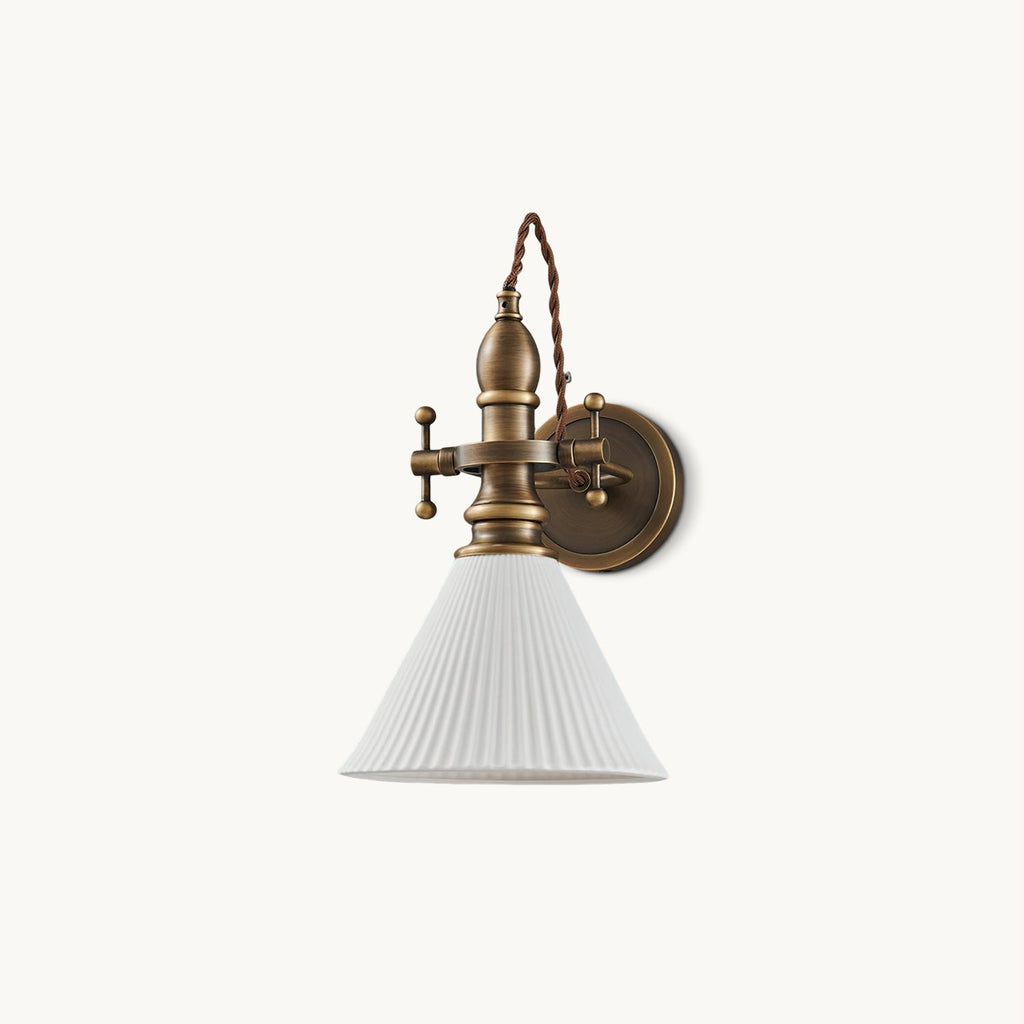Cut-out view of a Clérachic wall light with a white pleated cone shade on an antique brass arm, on a plain white backdrop.