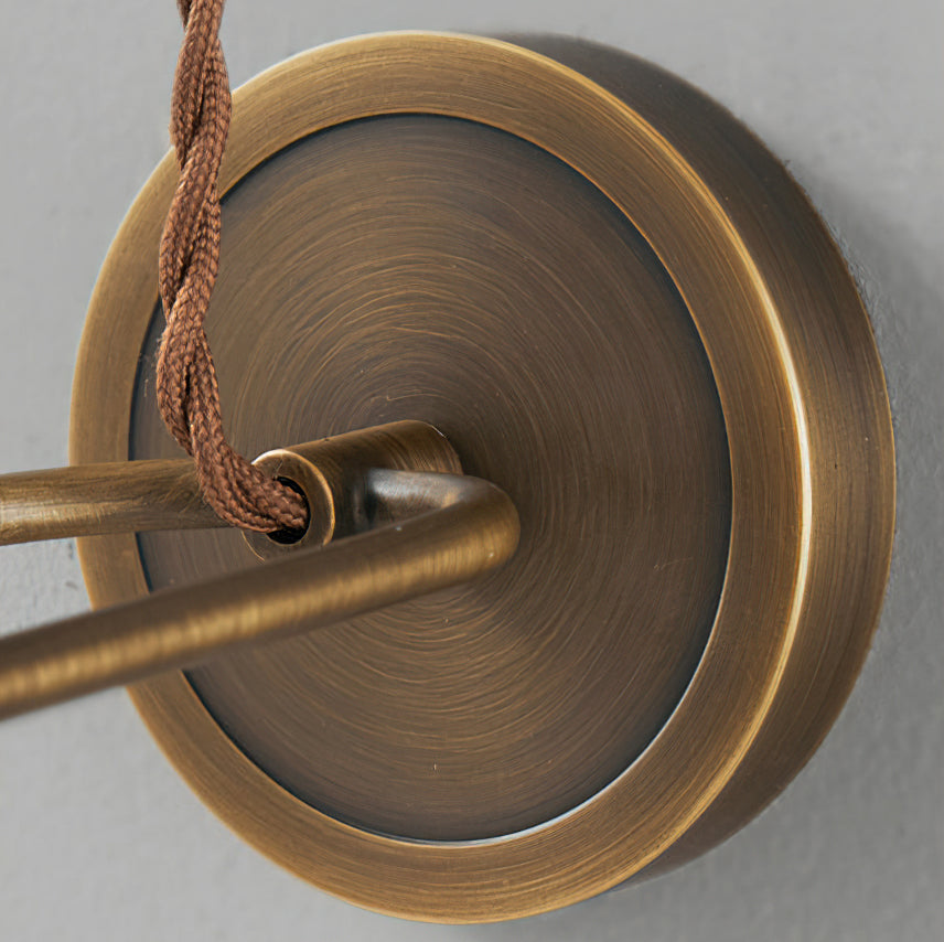 Close view of the brushed antique brass backplate and twisted brown cord entry on this Clérachic wall light.
