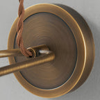 Close view of the brushed antique brass backplate and twisted brown cord entry on this Clérachic wall light.