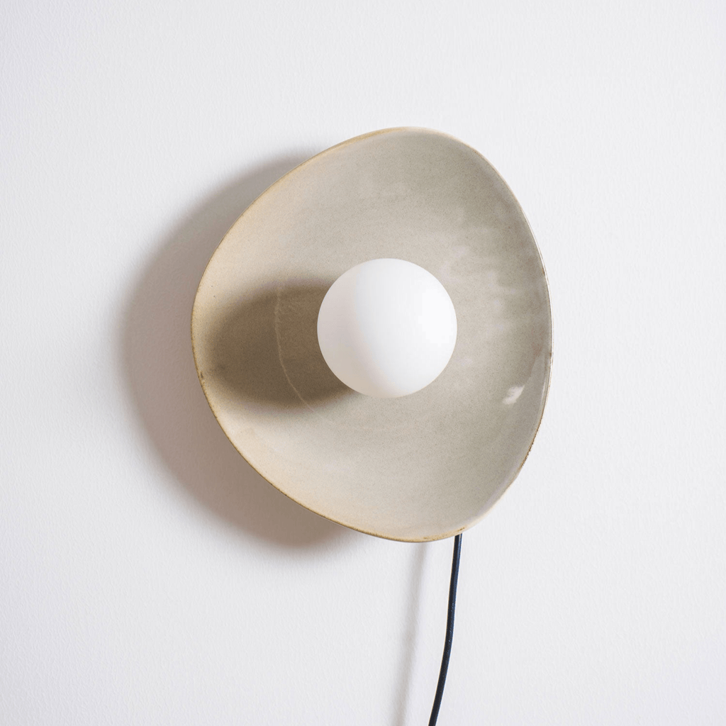 Large front view of the taupe glazed disc and white globe on this Clérachic ceramic wall light, with its cord dropping out of frame.
