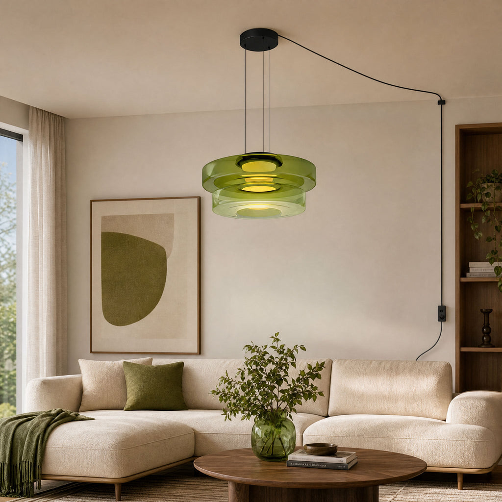 This Clérachic pendant in green glass hangs above a cream sofa, its cord looping to a wall plug.