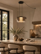 Two stacked smoke-grey glass discs on this Clérachic pendant hang above a marble kitchen island.