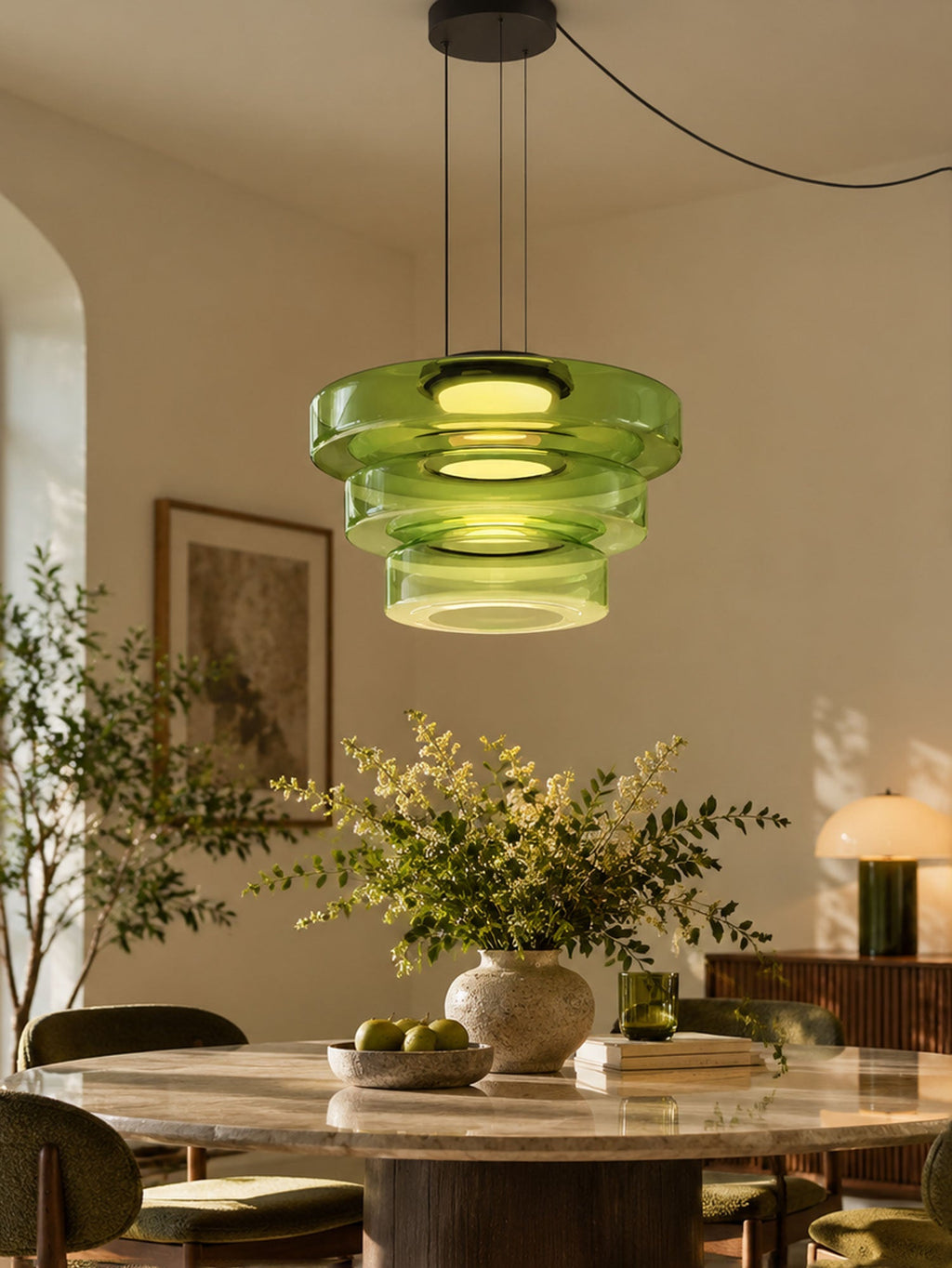 Green glass tiers on this Clérachic pendant hang above a dining table set with fresh greenery.