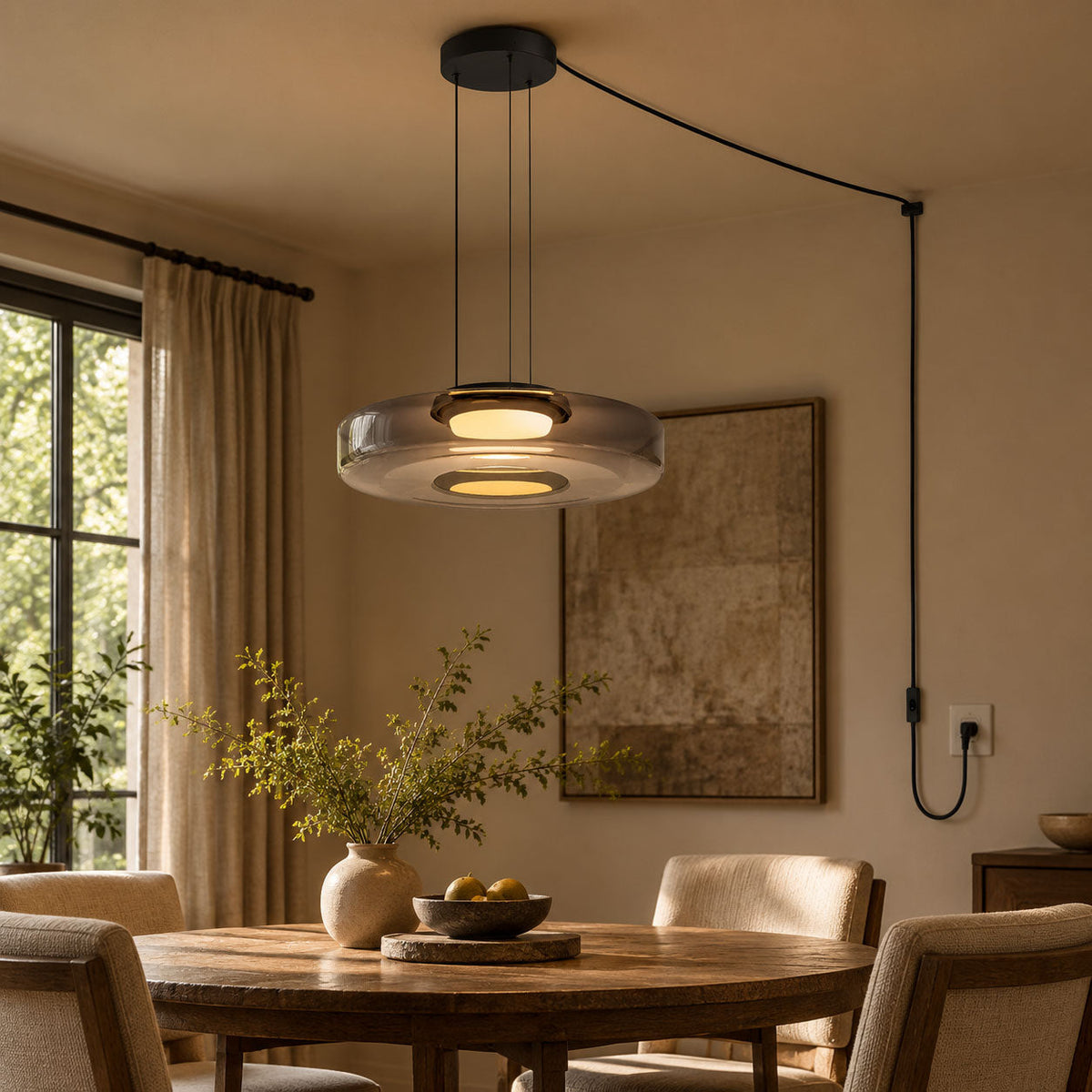 A single-tier Clérachic pendant in smoke-grey glass lights a long dining table, its cord plugged into the wall.