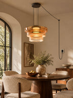 Amber glass tiers on this Clérachic pendant hang beside an arched window in a dining nook.