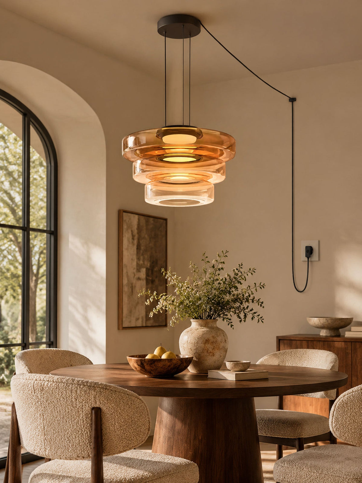 Amber glass tiers on this Clérachic pendant hang beside an arched window in a dining nook.