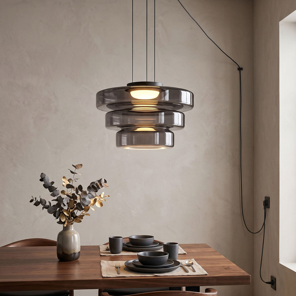 Three tiers of smoke-grey glass on this Clérachic pendant hang over a table set with dark stoneware.