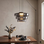 Three tiers of smoke-grey glass on this Clérachic pendant hang over a table set with dark stoneware.