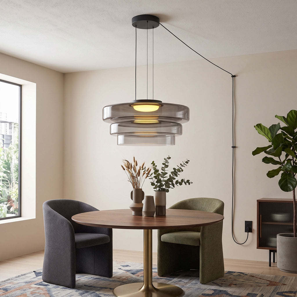 Smoke-grey glass tiers on this Clérachic pendant hang above a round table with black and green chairs.