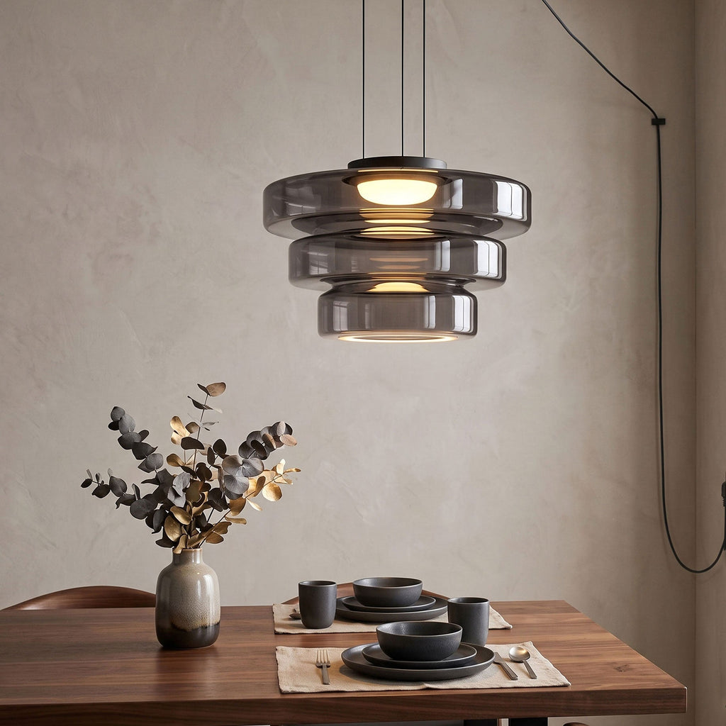 Set above a dinner table, this Clérachic pendant's three smoke-grey glass tiers catch the evening light.