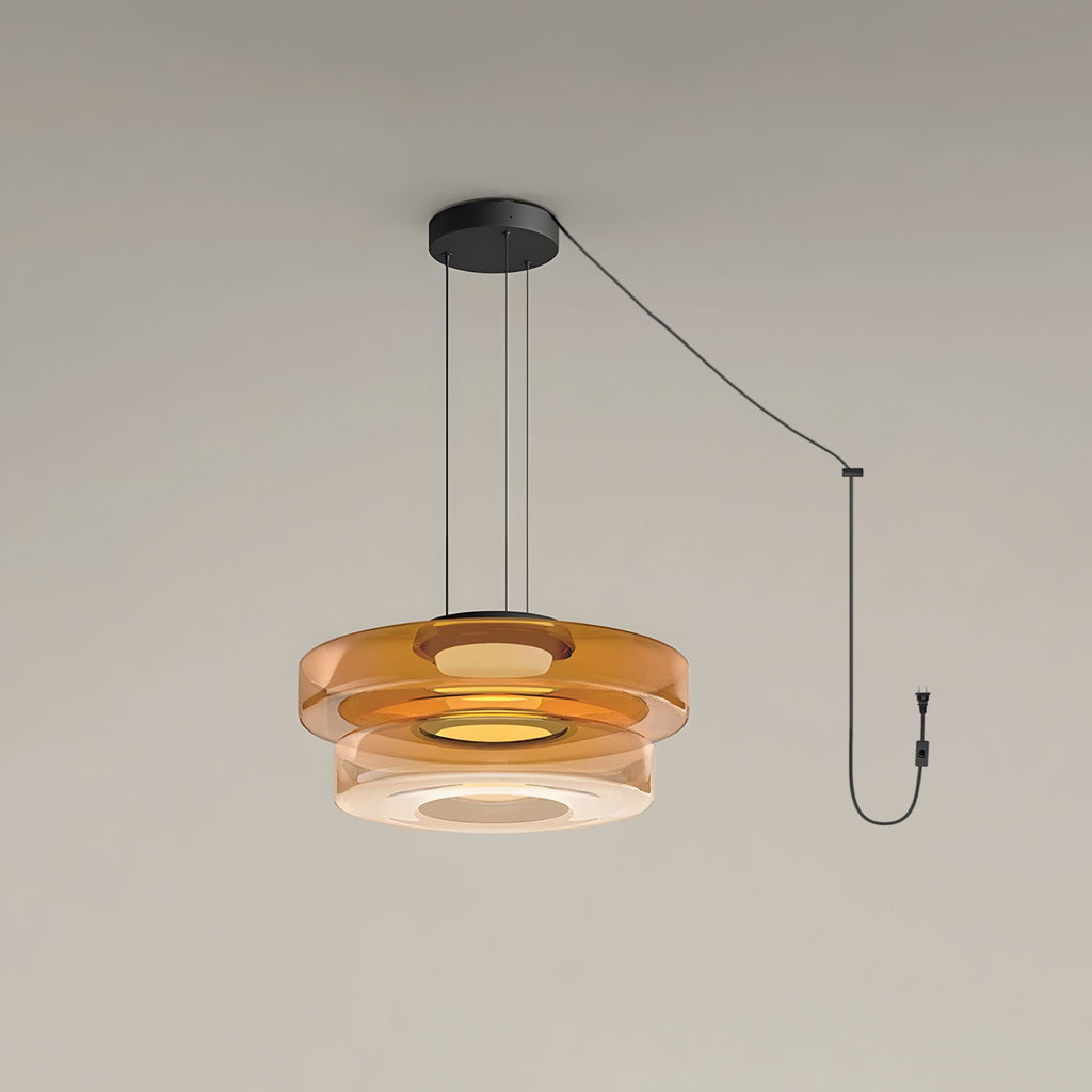 Two tiers of amber glass stack on this Clérachic pendant, cord looping to its plug.