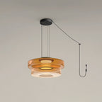 Two tiers of amber glass stack on this Clérachic pendant, cord looping to its plug.