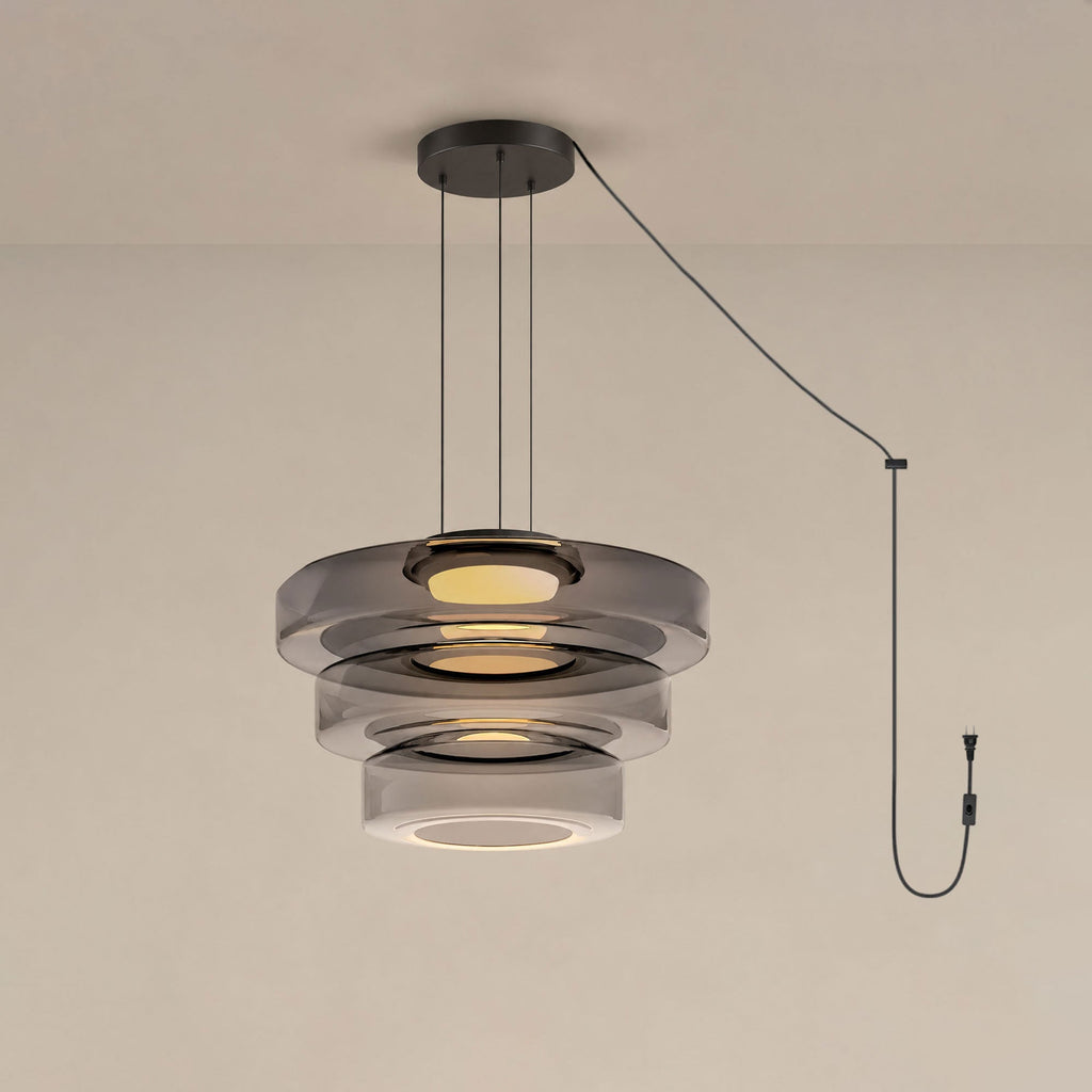 Three tiers of smoke-grey glass stack on this Clérachic pendant against a warm beige backdrop.