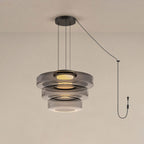 Three tiers of smoke-grey glass stack on this Clérachic pendant against a warm beige backdrop.