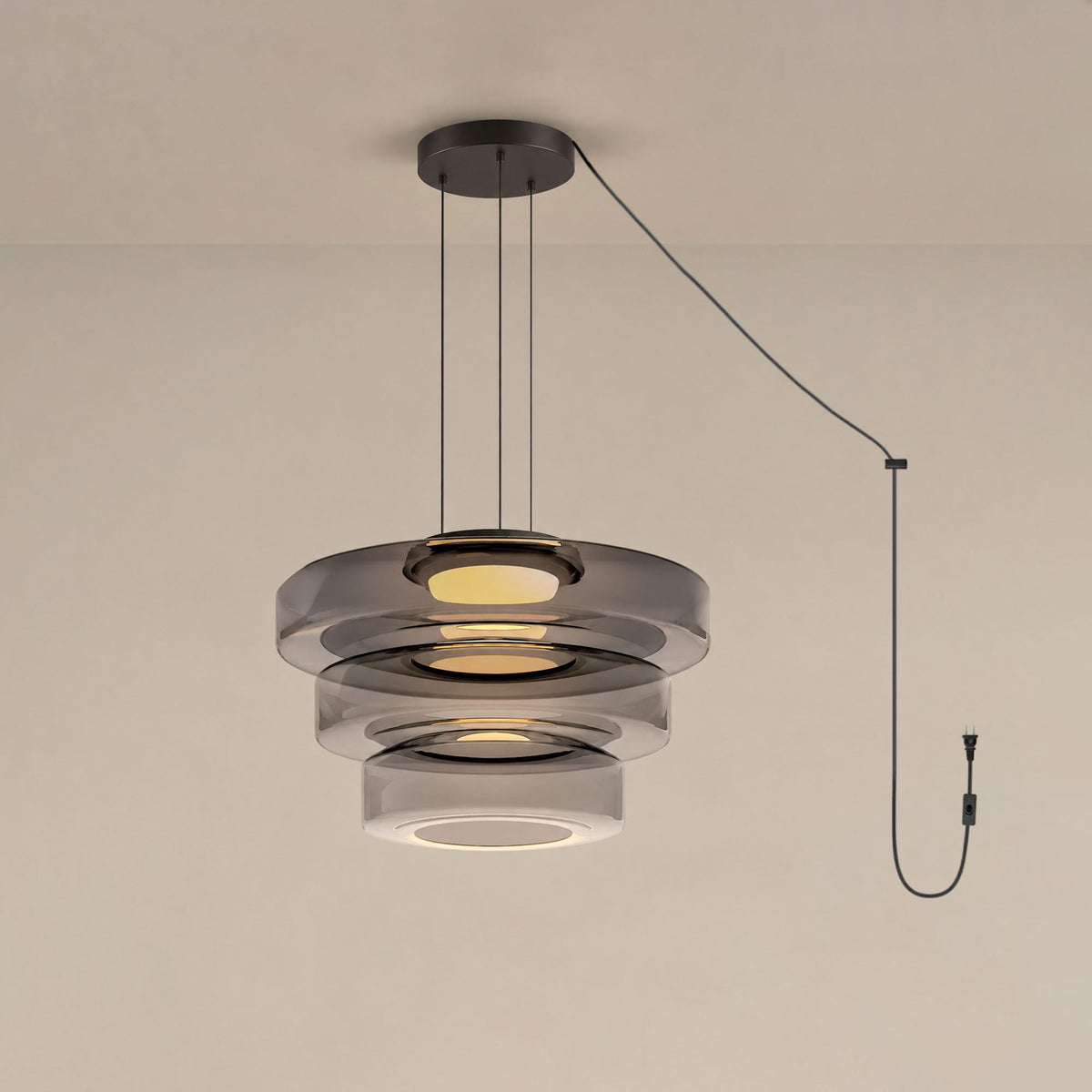 Three tiers of smoke-grey glass stack on this Clérachic pendant against a warm beige backdrop.