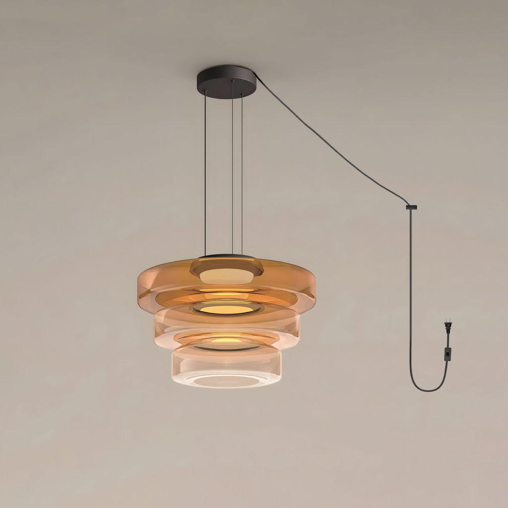 Three tiers of amber glass stack on this Clérachic pendant against a plain grey backdrop.