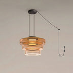 Three tiers of amber glass stack on this Clérachic pendant against a plain grey backdrop.