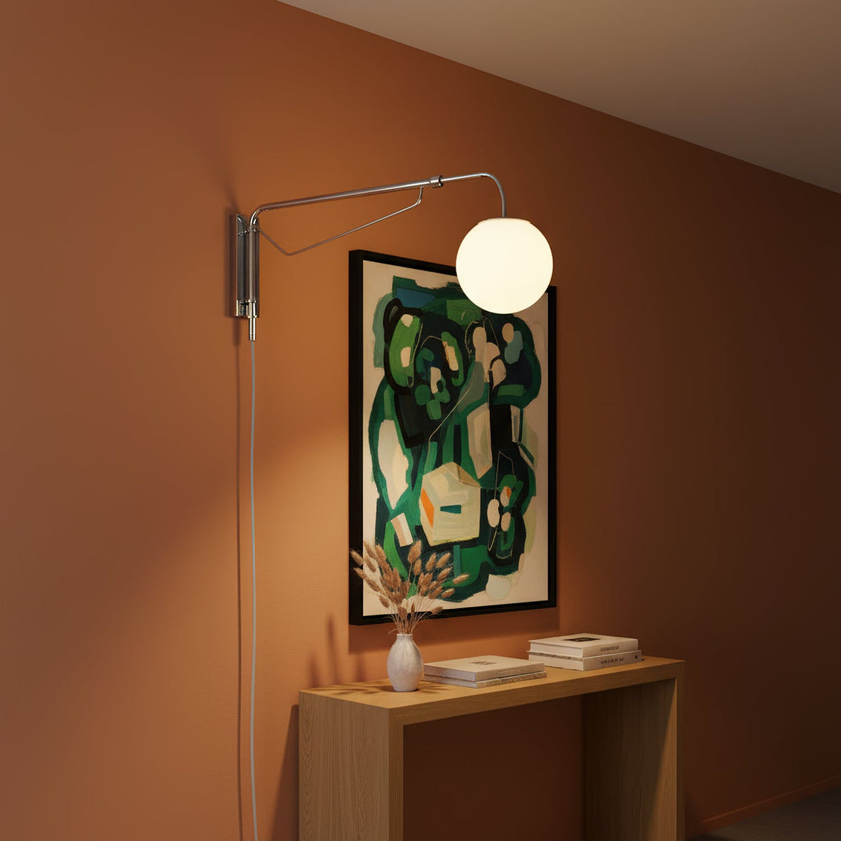 Chrome Clérachic plug-in wall light with a white globe on a terracotta wall, above a pale wood console and a green abstract print.