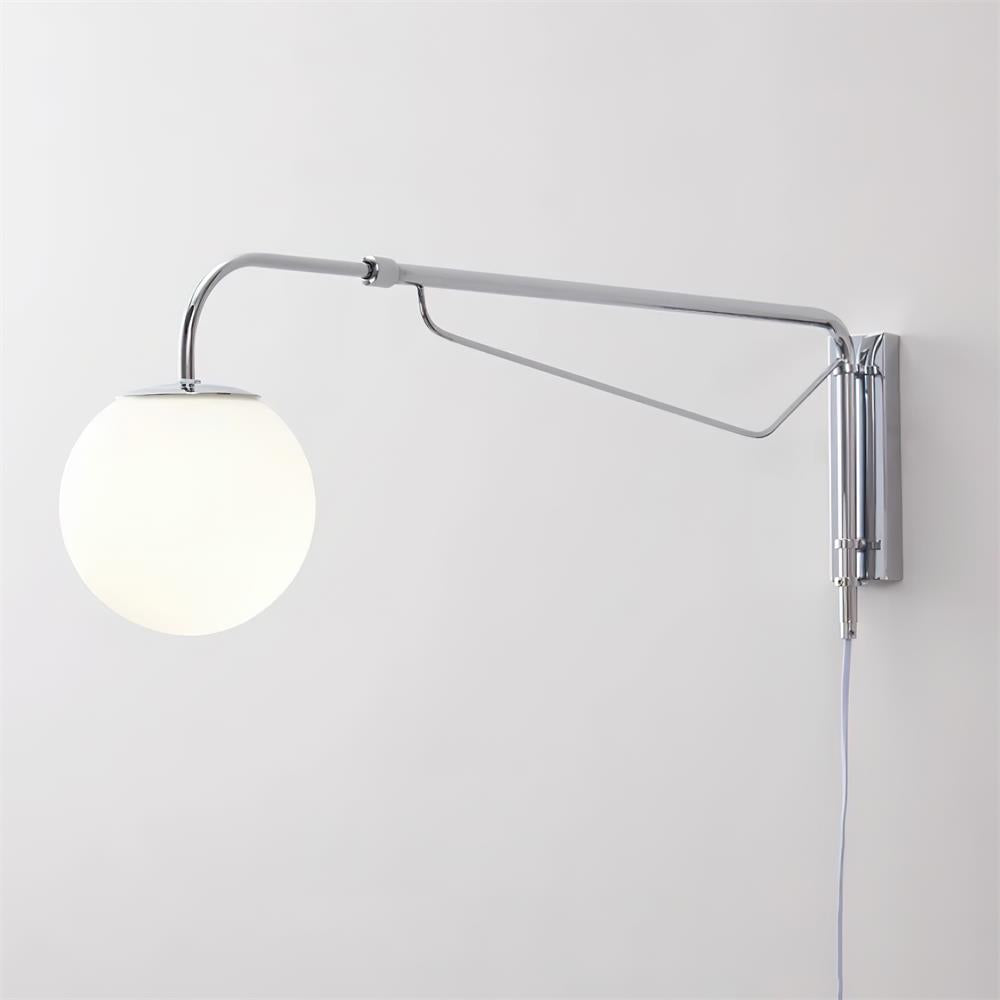 Close view of this chrome Clérachic wall light on a white wall, showing its long arm, diagonal brace and white globe.