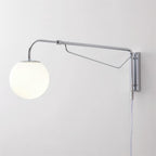 Close view of this chrome Clérachic wall light on a white wall, showing its long arm, diagonal brace and white globe.
