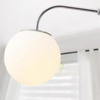 Close view of the large white globe on this Clérachic wall light, with a dashed arc marking its swing, and a window blind behind.