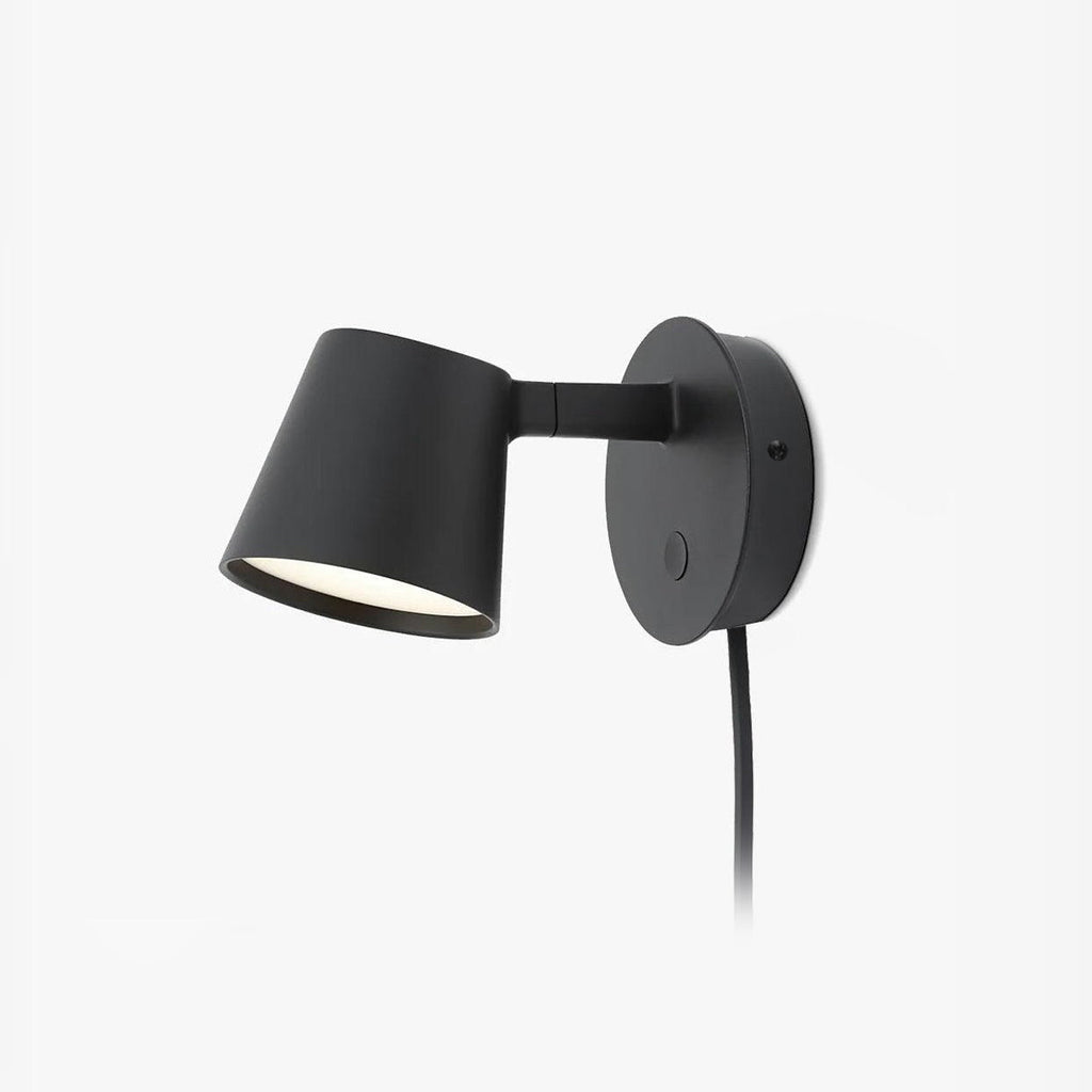 Black Clérachic plug-in wall light on a plain white backdrop, with a round backplate, angled arm and cone shade.