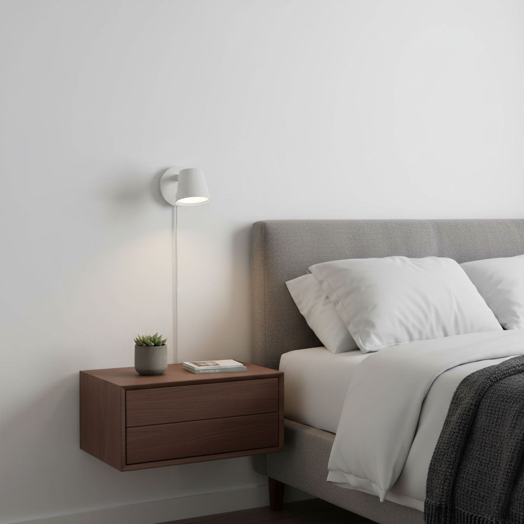 White Clérachic wall light with a slim cord above a walnut floating bedside unit, beside a grey upholstered headboard.