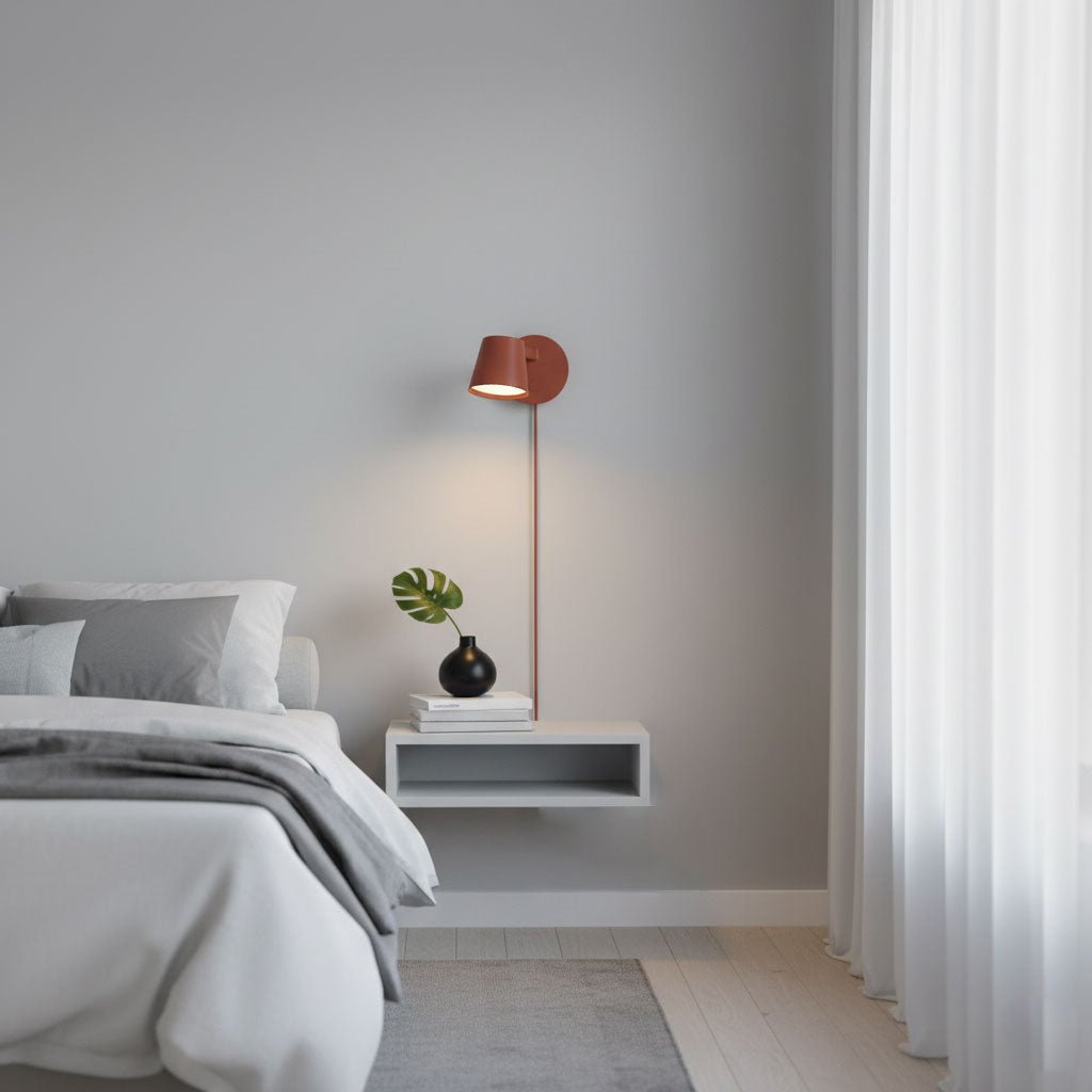 Red Clérachic wall light above a white floating shelf beside a bed, with soft curtains at the window.