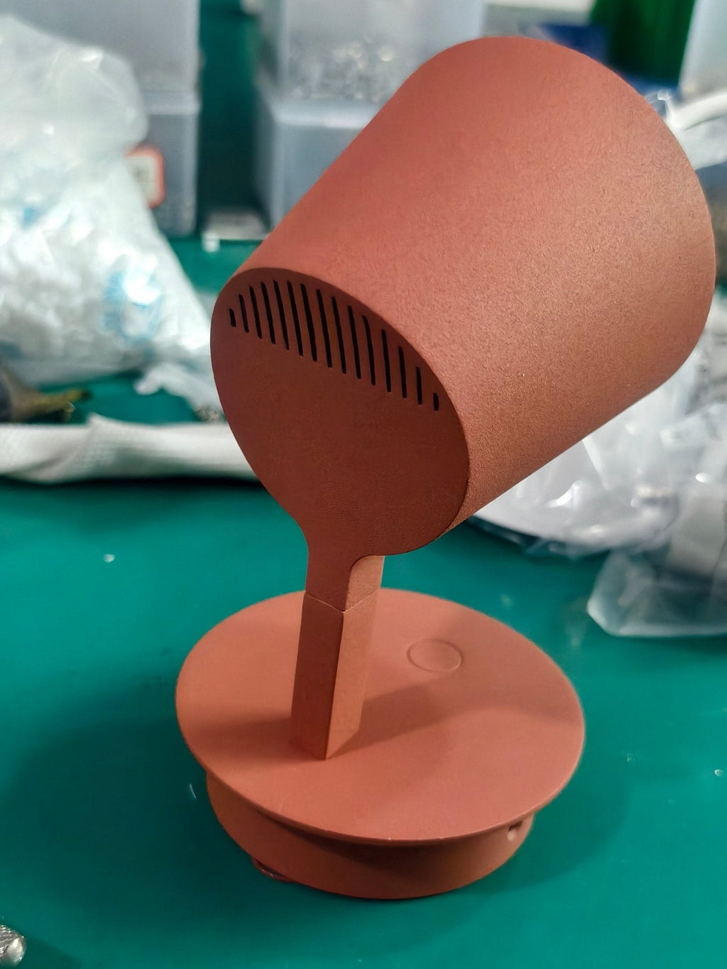 Red Clérachic wall light stood upright on a workbench, its vented shade tipped forward on the arm above the round base.