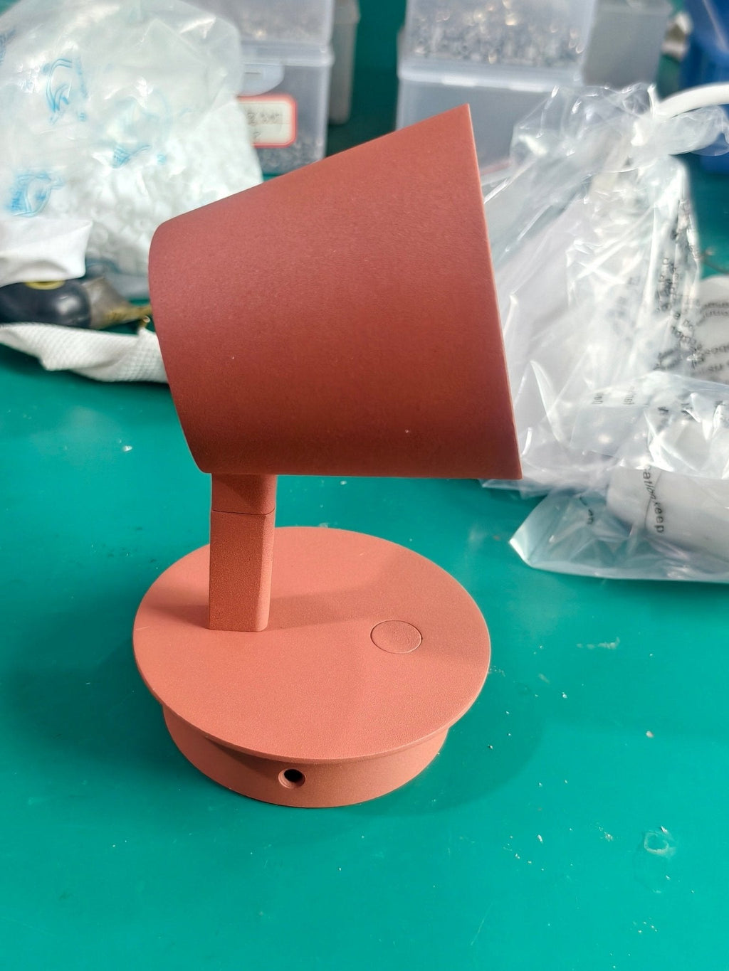 Red Clérachic wall light tilted on its arm, the cone shade seen from the side and the round backplate below.