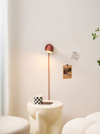 Distant view of a lit red Clérachic wall light above a ribbed cream side table, with boucle seating around it.